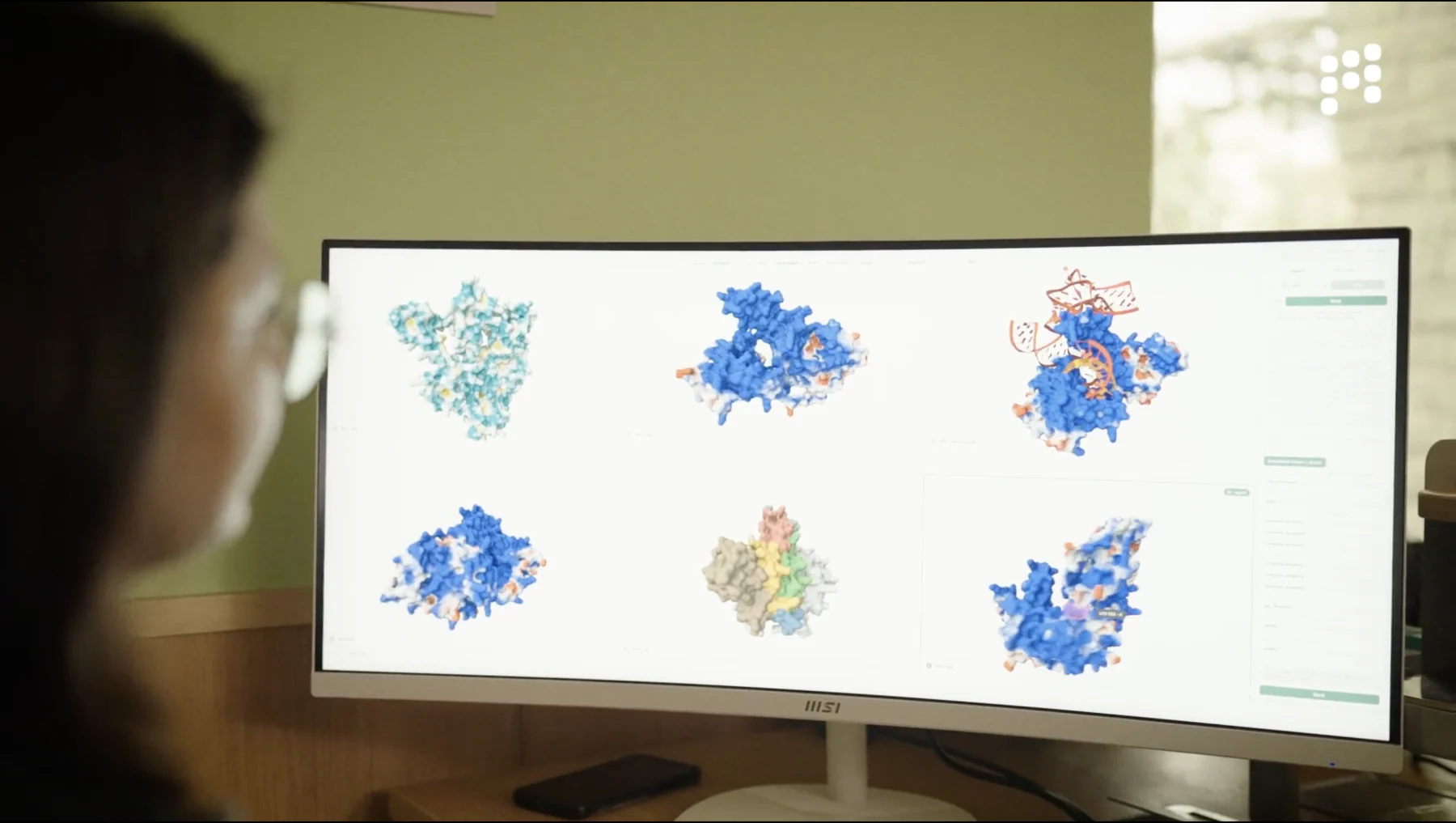 A Mandrake researcher reviewing protein structures at a design workstation